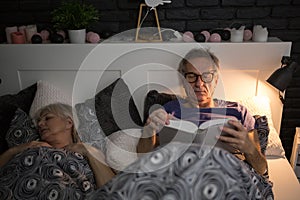Senior man reading book in bed before sleep