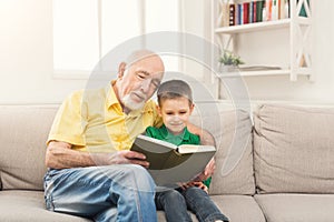 Senior man reading book for his grandchild