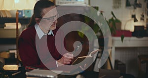 Senior Man Reading Book At Home At Dimmed Light At Night