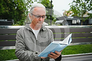 Senior man reading a book in the park.