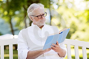 Senior man reading book at summer park