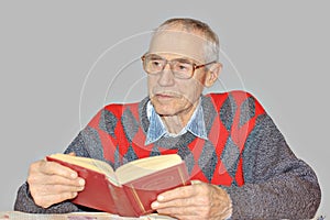 Senior man reading a book at the table