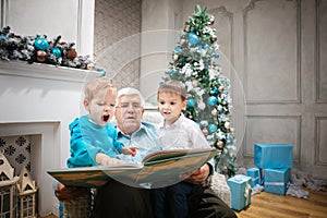 Senior man reading a book to grandsons