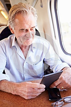 Senior Man Reading E Book On Train Journey