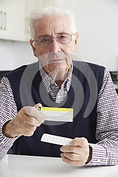 Senior Man Reading Information On Drug Packaging