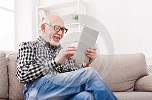 Senior man reading news on digital tablet