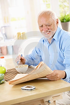 Senior man reading papers at breakfast