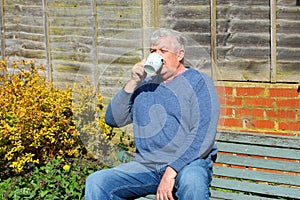 Senior man relaxing drinking coffee in garden.