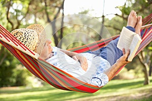 Senior Man Relaxing In Hammock With Book photo