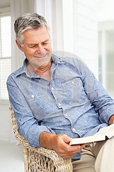 Senior man relaxing at home with a book