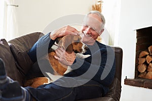 Senior Man Relaxing At Home With Pet Dog