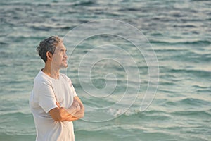 Senior man relaxing among the morning sunshine, background blurred sea water photo