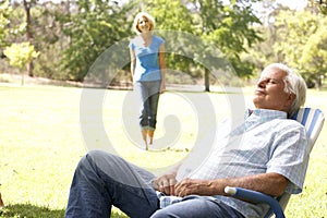 Senior Man Relaxing In Park With Wife