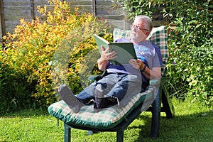 Senior man relaxing and reading on a sun lounger.
