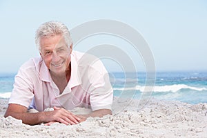 Senior Man Relaxing On Sandy Beach