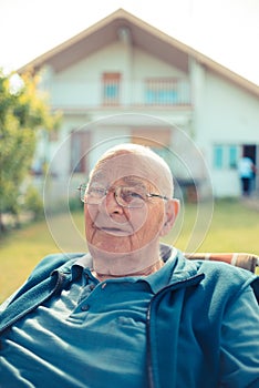 Senior man relaxing sitting in front of his house