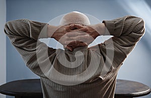 Senior man relaxing and sitting with hands behind head