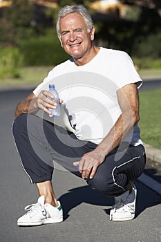 Senior Man Resting And Drinking Water After Exercise