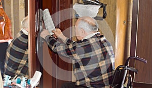 Senior man retrieving a newspaper through a door