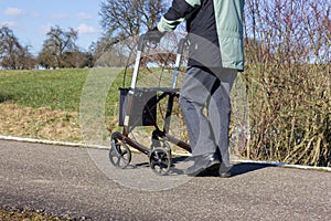 senior man with rollator on a bikeway and sunny winter day