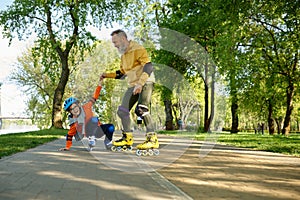 Senior man roller skating with little boy in urban park