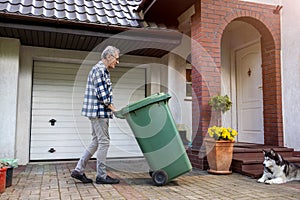 Senior man rolling garbage can