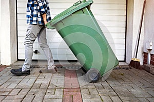 Senior man rolling garbage can