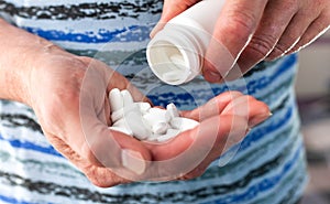 Senior man`s hands holds a white bottle and white pills. Medical concept. Caring for the health of the elderly. Close-up