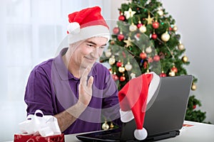Senior man with santa claus hat talking with family and waving