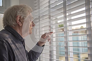 Senior man with serious facial expression loooking out of window