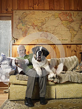 Senior Man Sharing Sofa With Large St Bernard Dog