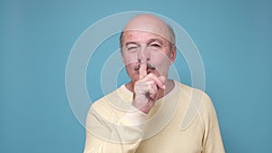 Senior man with shh gesture, asking for silence or to be quiet