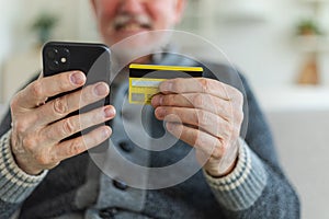 Senior man shopping online holding smartphone paying with credit card Old grandfather buying on Internet enter credit