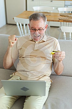 Senior man shopping online using laptop paying with credit card. Old grandfather buying on Internet enter credit card