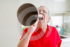 Senior man shouthing excited through vintage metal megaphone