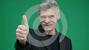 Senior man show thumbs up, good gesture, isolated on green