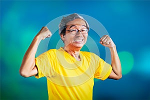 Senior Man showing off muscle for strong healthy lifestye concept on blue bokeh background photo