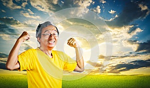 Senior Man showing off muscle for strong healthy lifestye concept with golden nature sky background photo