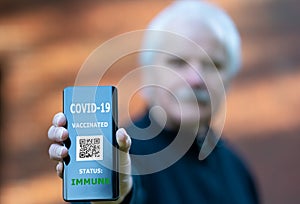 Senior man showing an vaccination certificate on a mobile phone, which indicates a vaccination against covid-19