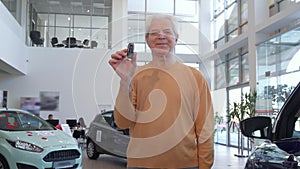 Senior man shows car key at the dealership