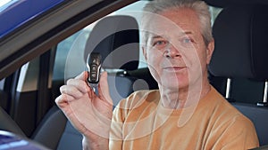 Senior man shows car key through the window