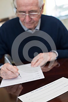 Senior Man Signing Last Will And Testament At Home