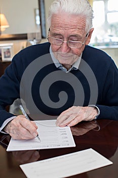 Senior Man Signing Last Will And Testament At Home photo