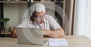 Senior man sit at table use laptop make video call