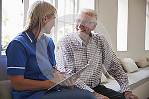 Senior man sits with nurse making notes at retirement home