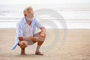 Senior man sitting on beach relaxing . Happy retired man relaxed on sand outdoors