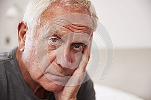 Senior Man Sitting On Bed At Home Suffering From Depression