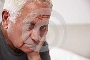 Senior Man Sitting On Bed At Home Suffering From Depression