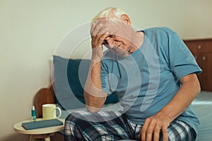 Senior Man Sitting On Bed Suffering From Depression