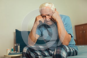 Senior Man Sitting On Bed Suffering From Depression